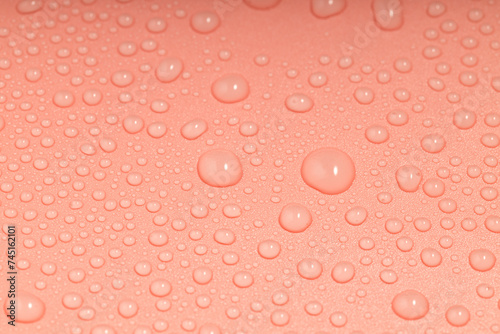 the orange surface is covered with water droplets of different sizes