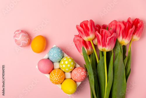 Easter eggs with a bouquet of tulips on a bright pink background. Easter celebration concept. Colorful easter handmade decorated Easter eggs. Place for text. Copy space.