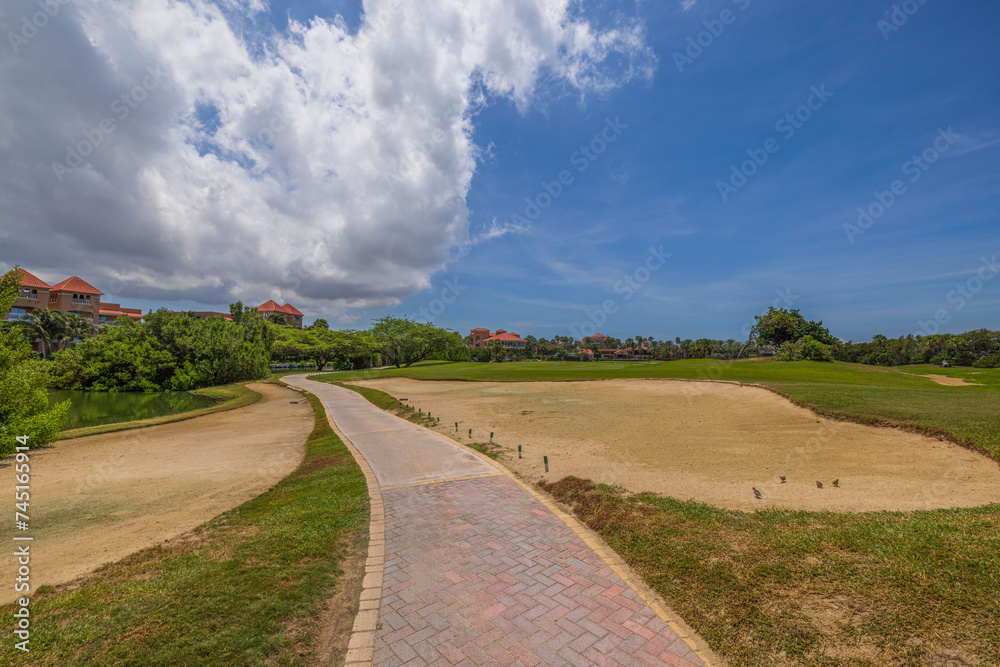 Gorgeous tropical scenery featuring a golf course against the canvas of a blue sky with white clouds. Aruba.