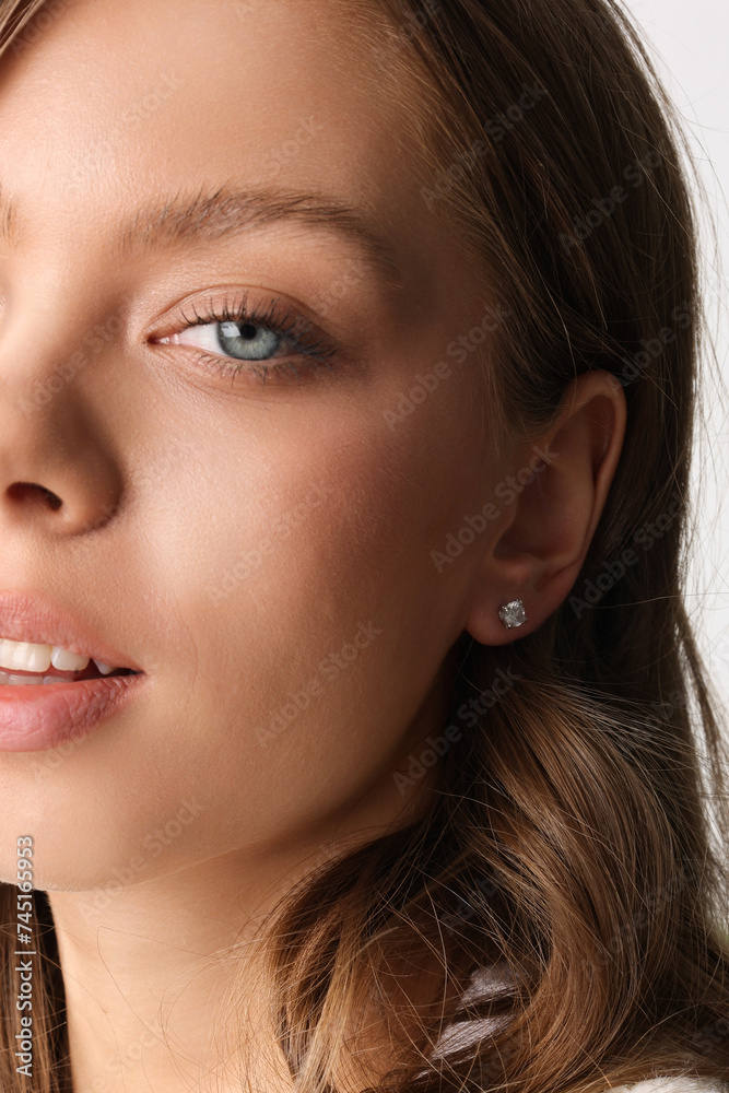 Obraz premium Beautiful young girl with fresh healthy skin. Woman advertise ear-rings. White background. Earrings closeup. Blond european woman with long hair with big lips, pretty smile. Cosmetology, scincare