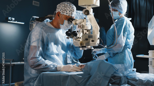 A surgeon looks through a microscope in the operating room. A doctor uses a microscope during eye surgery or diagnosis, cataract treatment and diopter correction. photo