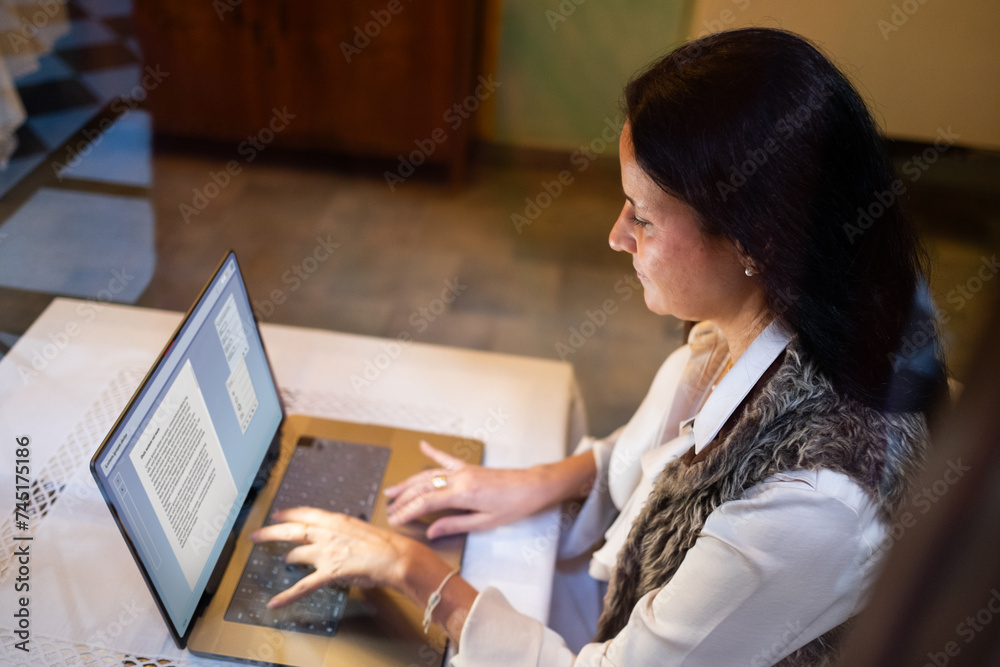 elegant and beautiful middle-aged woman teleworks with a laptop computer in a coffee shop.