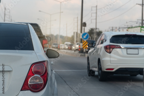 Rear side view of white car with tail lights. Environment of car in the day time. Rush hour in the city. Traffic jam on the road in Thailand. 