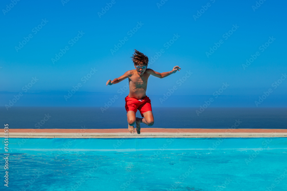 Cute tanned teen in goggles jump carefree at a seaside pool Cute tanned teen in goggles jump carefree at a seaside pool