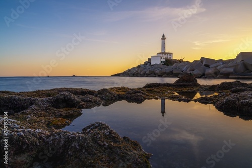 landscape view of the Botafoc Lighthouse in Ibiza Town Port at sunsetwith reflections in tidal pools in the foreground