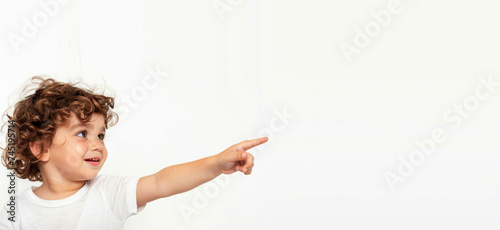 A little boy points his finger on an isolated light-colored background with free space generated AI