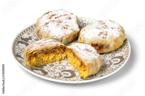  Plate with fresh baked Moroccan whole and halved mini bastella stuffed with chicken and covered with sugar and cinnamon close up isolated on white background