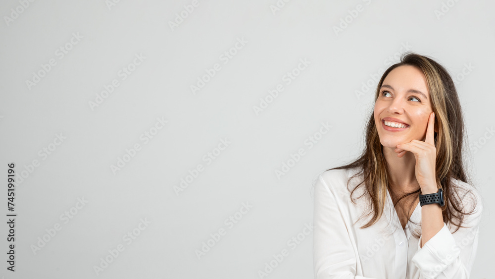 Dreamy young woman with a joyful smile looking upwards, resting her face on her hand Dreamy young woman with a joyful smile looking upwards, resting her face on her hand