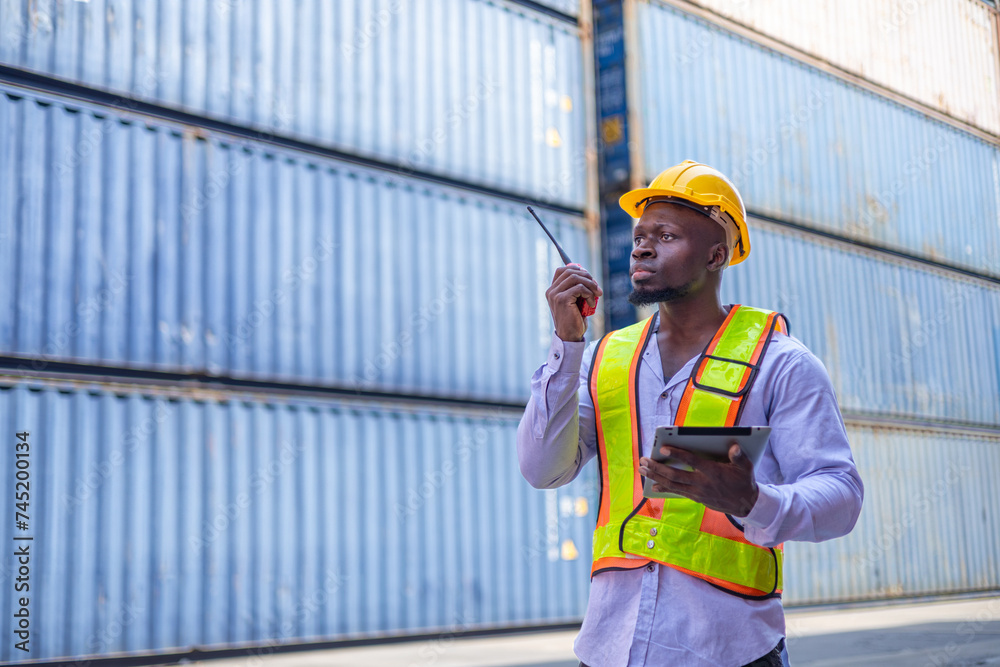 Black engineer in warehouse inspecting goods at industrial container yard Black engineer in warehouse inspecting goods at industrial container yard
