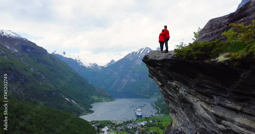 A couple in love embrace and look at the infinitely beautiful panorama of Geirangerfjord fjord in Norway. Inspirational travel video 4k