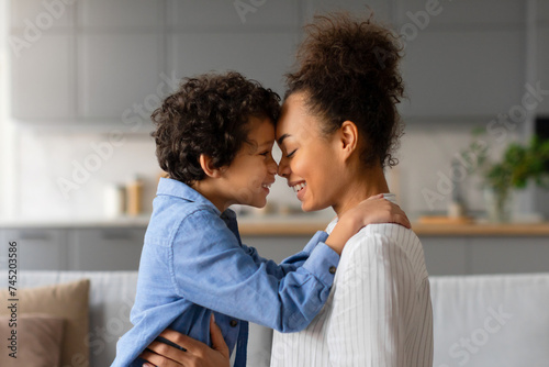 Loving moment as black mother and son share tender forehead touch photo
