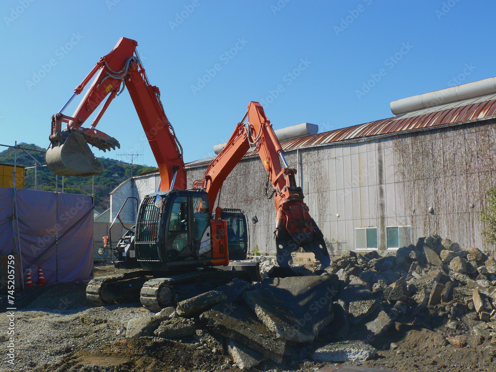 解体現場で稼働中の重機二台。
ビル取り壊し後のコンクリート破片を処理中。