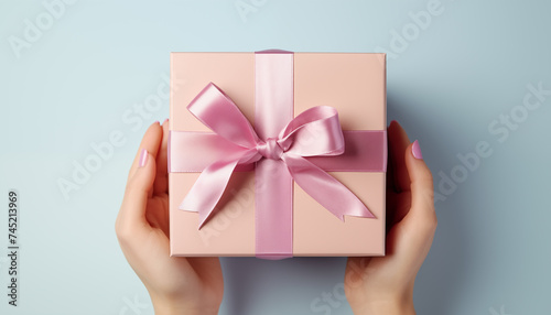 giving a gift. hands holding a gift on a pastel background.