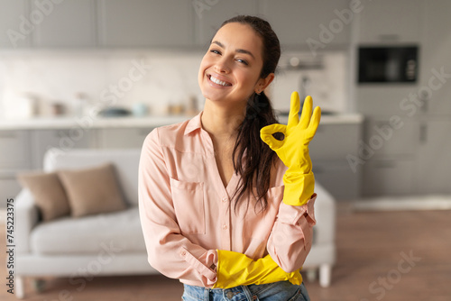 Smiling woman with yellow gloves giving okay sign photo