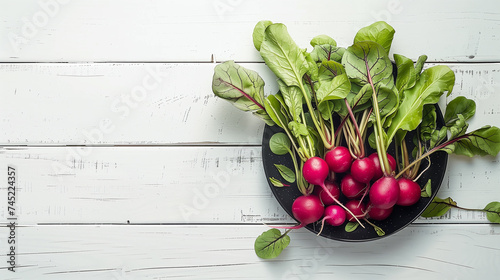 Fresh radishes in a bowl on white wooden background, top view