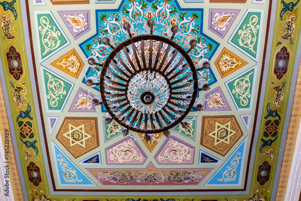 Obraz premium Kutaisi Synagogue inside view of richly decorated ceiling with colorful geometric and floral pattern paintings and chandelier.