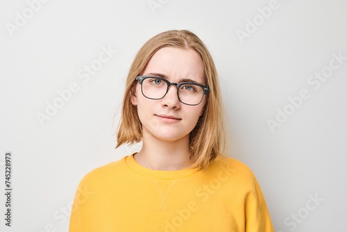 Portrait of girl with glasses wearing yellow top looking at the camera with neutral expression photo