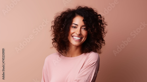 Close up of young woman with white skin  brown hair  wavy hair and a clear rose gold orange t shirt  isolated in a light orange studio. Portrait person.