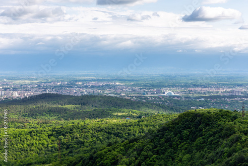 Kutaisi cityscape seen from Sataplia Nature Reserve with Former Georgian Parliament Building and green hills and Colchis forests around, summer, Georgia.