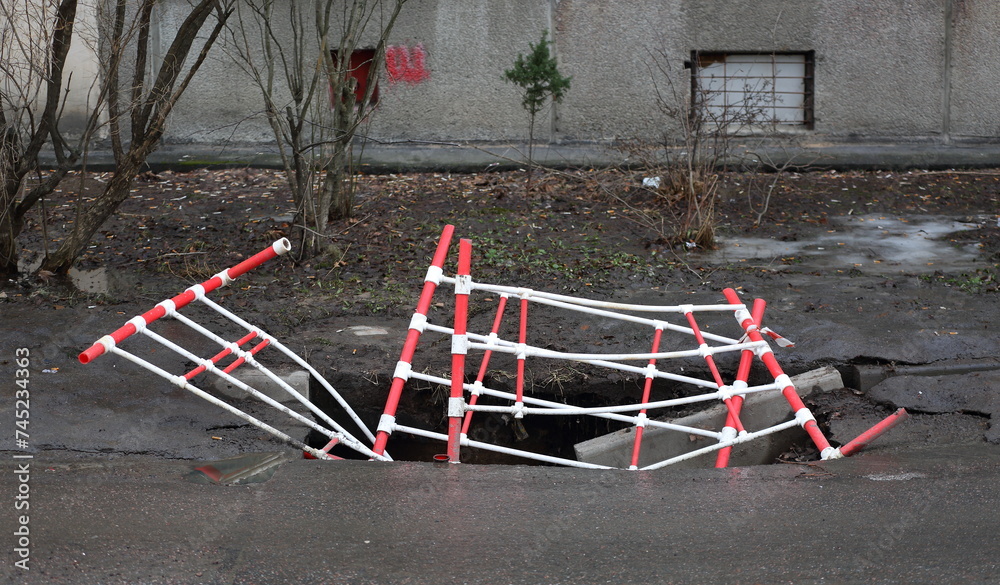 Red and white plastic barriers that fell into the pit at the site of a small utility accident Red and white plastic barriers that fell into the pit at the site of a small utility accident
