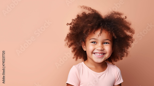 Close up of girl with brown skin, brown long hair, wavy hair and a clear pink t shirt, isolated in a light orange studio. Portrait person. © Sittipol 