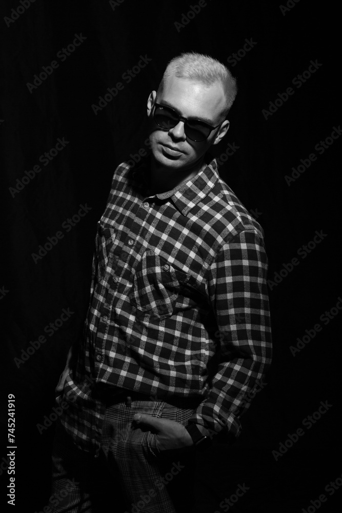 Portrait of a man in sunglasses and a plaid shirt on a black background. Portrait of a man in sunglasses and a plaid shirt on a black background.