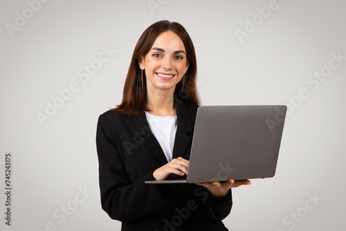 Professional businesswoman holding a laptop with a pleasant smile