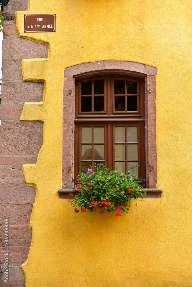 a stone window within a gold plaster facade building in french village