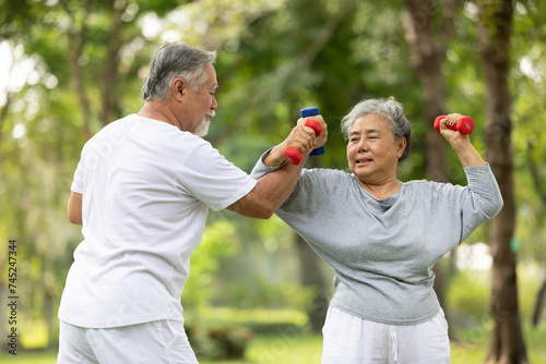 senior couple exercising and lifting dumbbells in the park