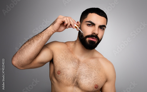 Attractive arab guy using hair growth for his beard photo