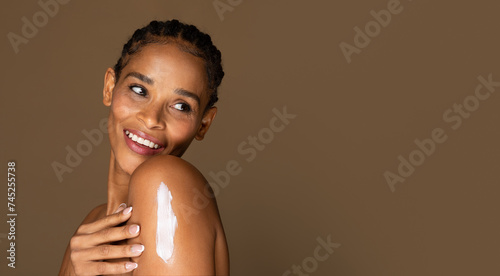 Foto Joyful african american middle aged woman with lotion on shoulder