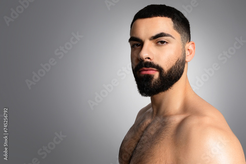 Closeup photo of Middle Eastern guy posing shirtless on grey