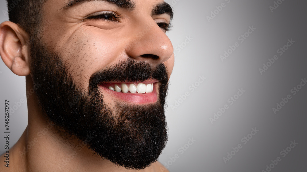 Obraz premium Closeup of handsome smiling middle eastern man posing on grey