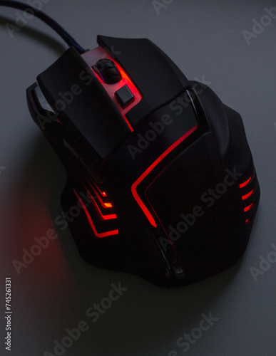 A black gaming mouse with a red light  in dark tone