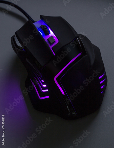 A black gaming mouse with a purple light  in dark tone