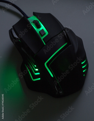 A black gaming mouse with a green light in dark tone