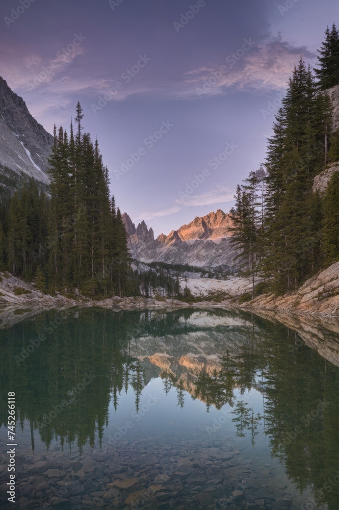 Grand mountain cliffs mirrored in serene alpine lake under evening sky 