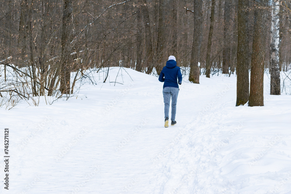 unrecognizable young beautiful athletic girl is engaged in race walking in the winter forest