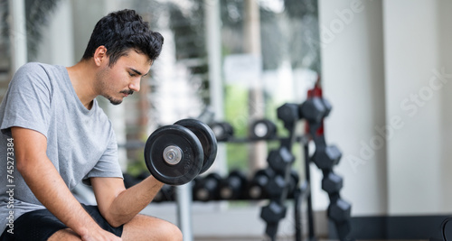 A moment of contemplation and preparation, as a man gets ready to embark on his weightlifting journey, showcasing the mental aspect of physical fitness. Gym workout concept.