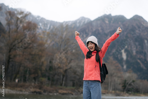 Asian woman in a pink fleece enjoys the freedom of a snowy adventure. Elegant portrait by the lake, capturing the excitement and exploration of a scenic journey.