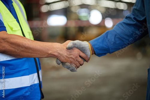 closeup worker shaking hands with coworker before starting work in the factory