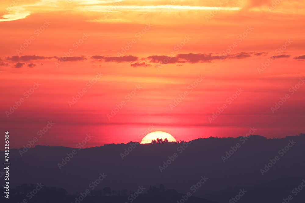the sun rises behind a mountain range in Piedmont