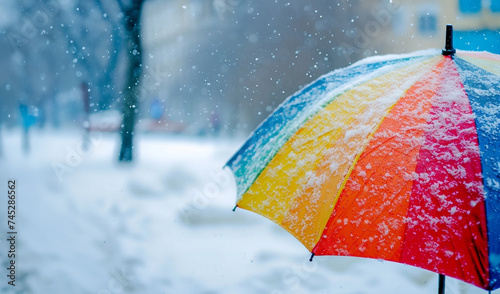 Rainbow umbrella under heavy snow in park. World meteorological day