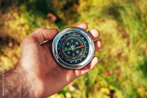 A compass in a man's hand illuminated by the sun