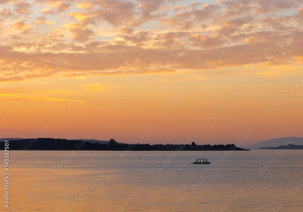 A boat sailing on a lake at the sunset