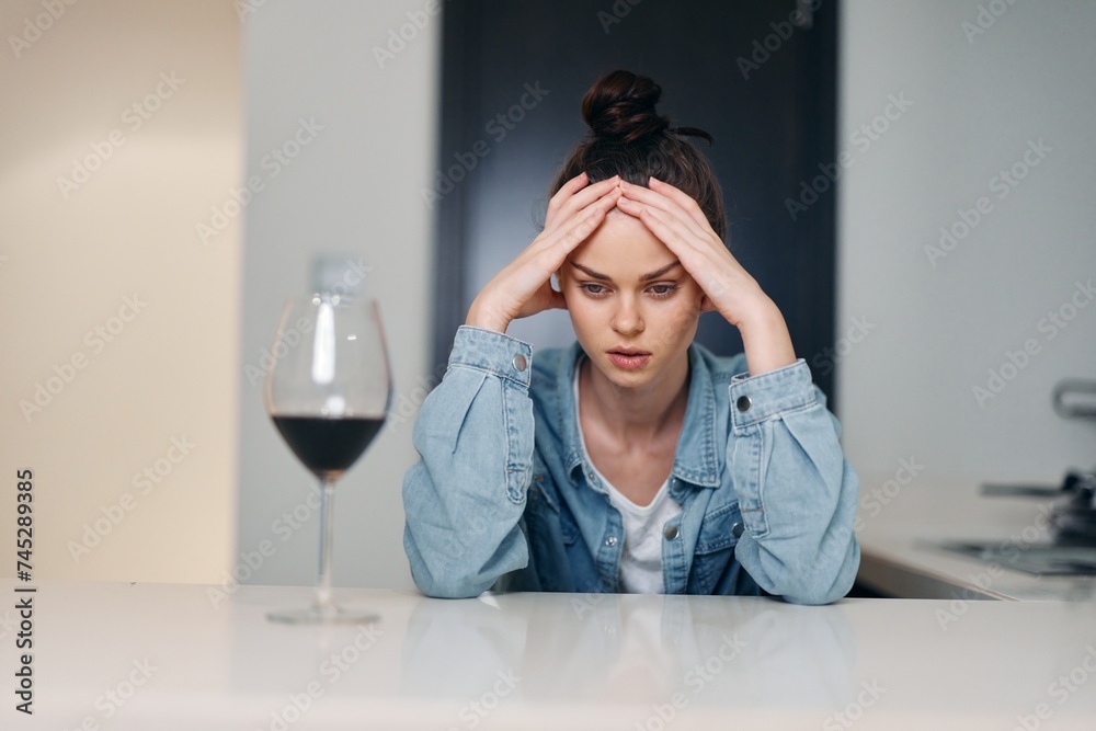 Lonely Woman Sitting at Home, Holding a Glass of Alcohol, Expressing Sadness and Pain Lonely Woman Sitting at Home, Holding a Glass of Alcohol, Expressing Sadness and Pain