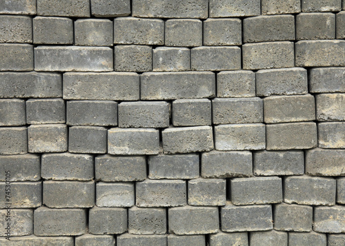 The surface of a wall or fence lined with gray bricks. Paving slabs of grey blocks of flat shape. Pavement blocks in city park. Park way materials. Bricks or blocks of paving slabs laid in row