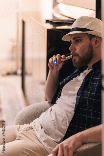 Portrait of a man smoking vape on his living room couch. Lifestyle concept