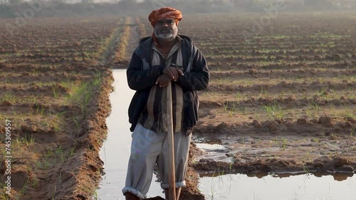 Indian farmer standing at agriculture field,Indian Rural Villager Farmer standing in field holding hoe, happy Indian farmer in rural India concept