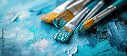 This close-up shows three paint brushes neatly arranged on a wooden table, each showcasing different bristle styles and lengths. The table surface reflects the light, highlighting the details of the
